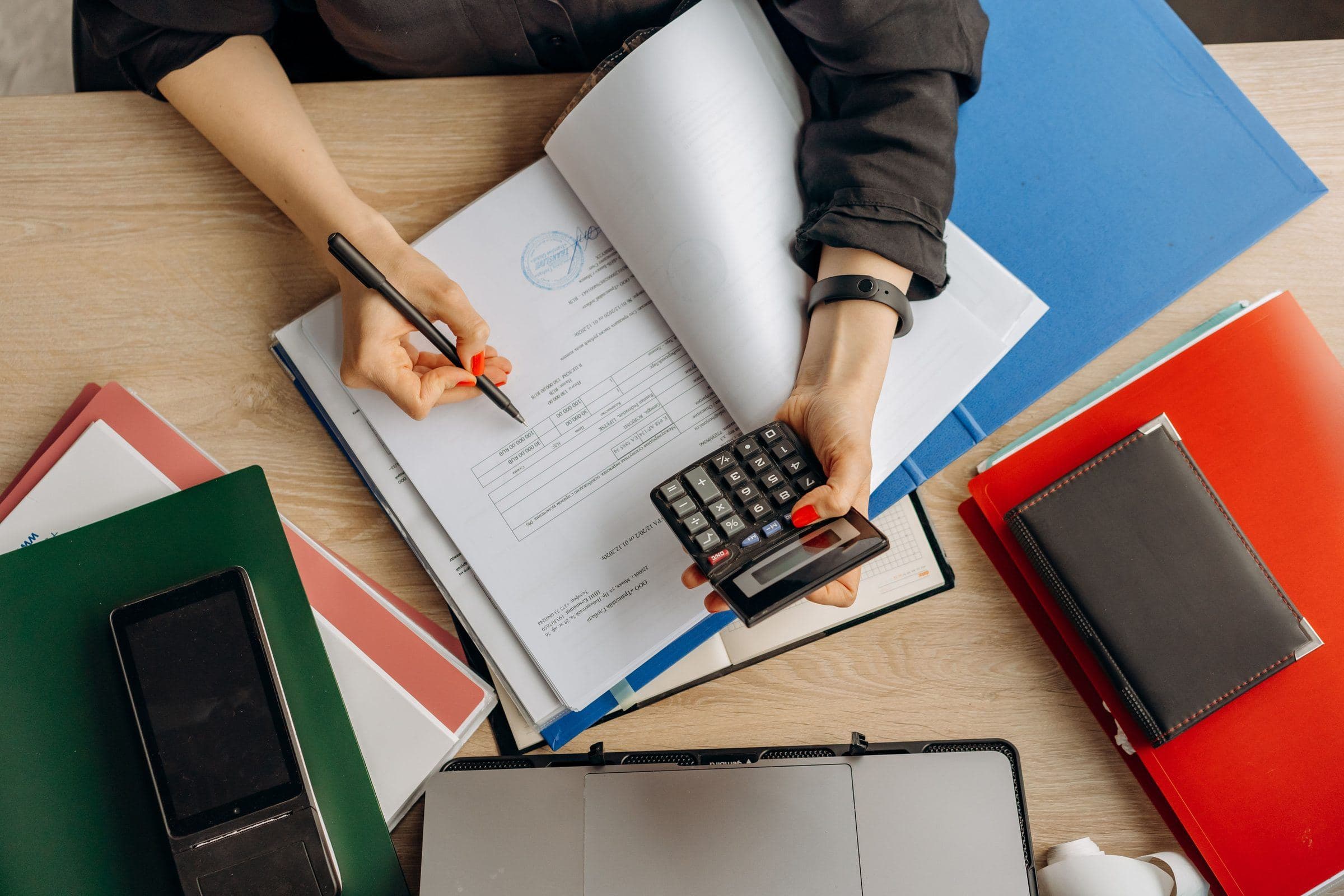 Financial charts, calculator and pen on an office desk